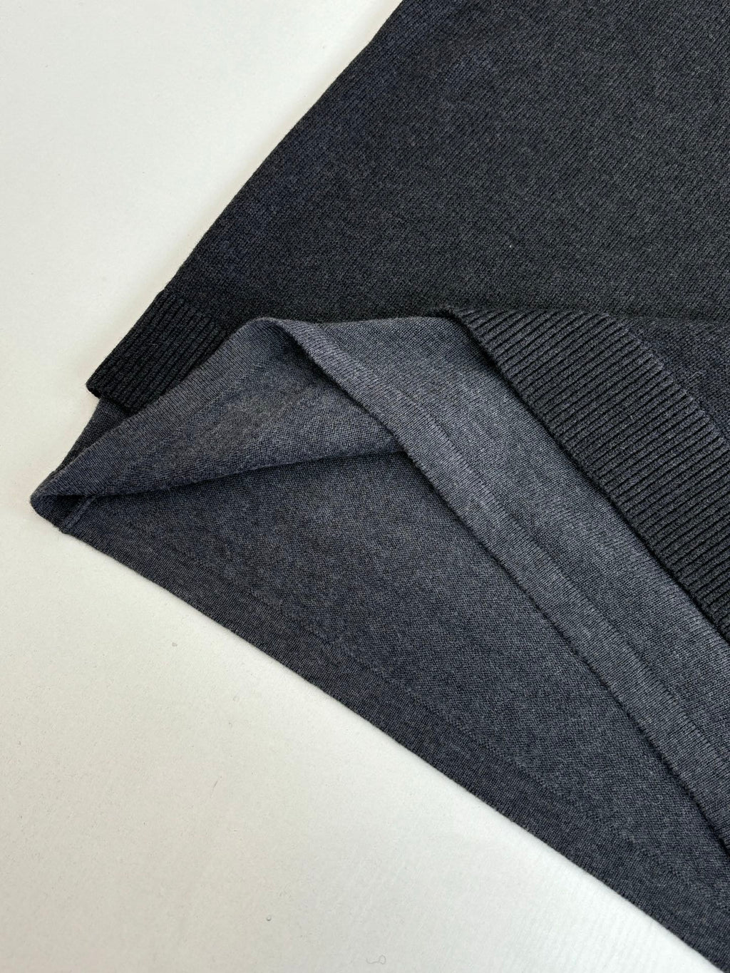Dark knit sweater with ribbed cuff detail and folded fabric layers