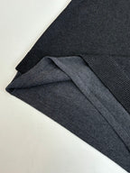 Dark knit sweater with ribbed cuff detail and folded fabric layers