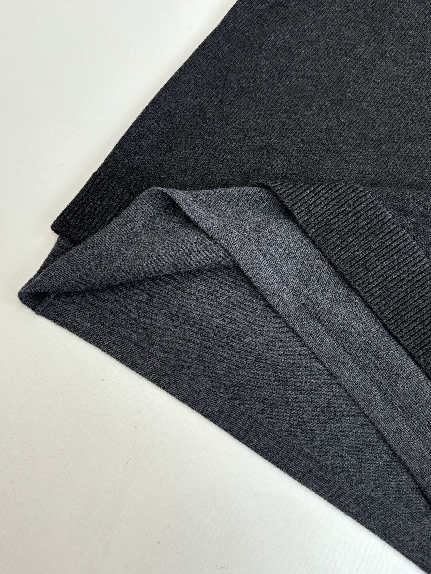 Dark knit sweater with ribbed cuff detail and folded fabric layers