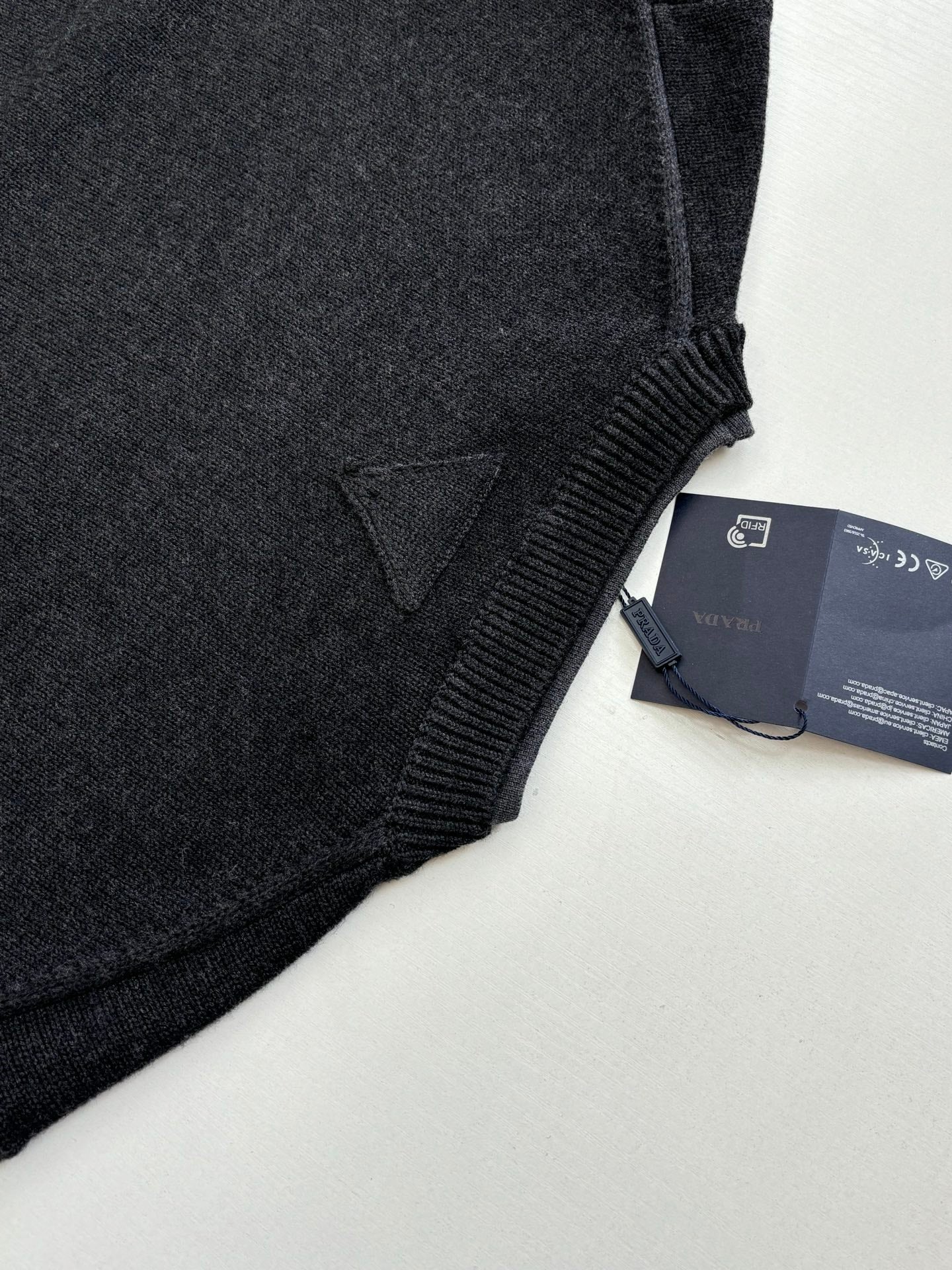 Dark knit sweater hem seam with hang tag attached