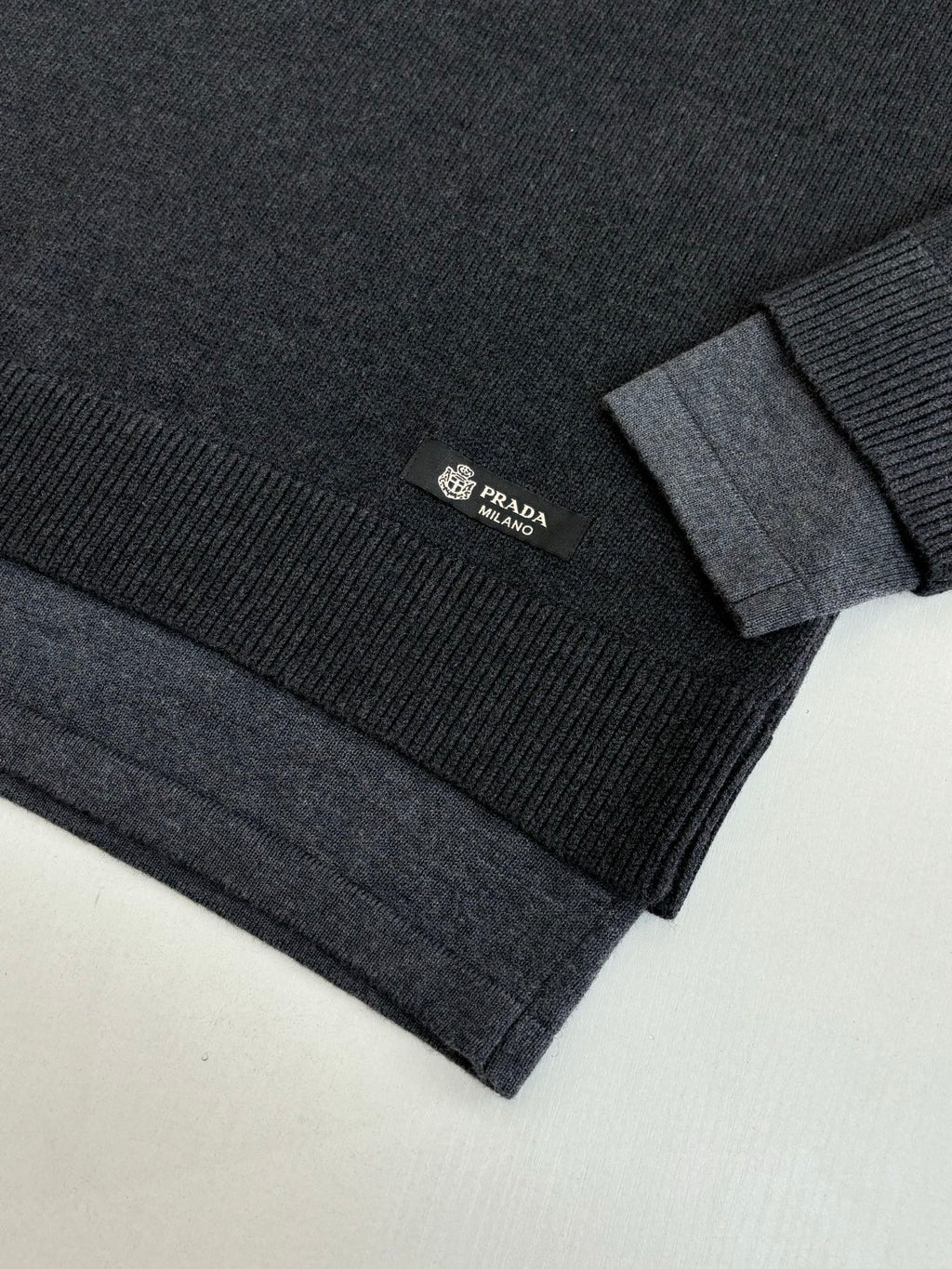 Dark knit sweater sleeve and hem detail with Prada logo patch