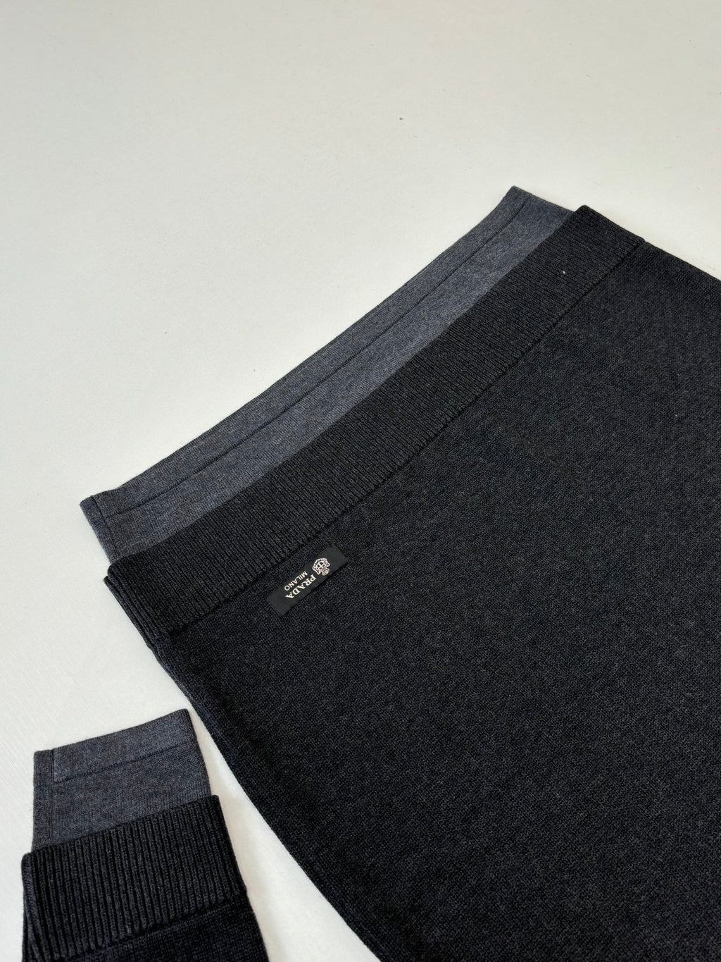 Dark knit sweater folded view with ribbed hem and small Prada tag