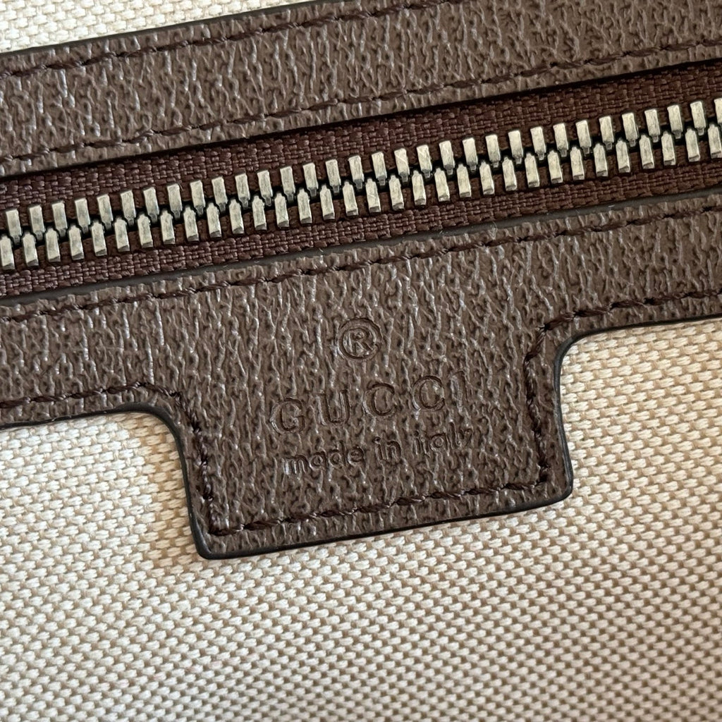 Duffel bag close-up of embossed logo on brown leather trim and zipper track