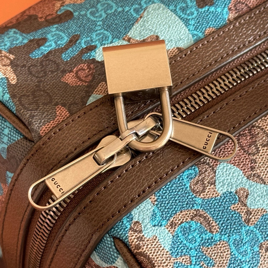 Duffel bag close-up of metal clasp, zipper pull, and brown leather trim