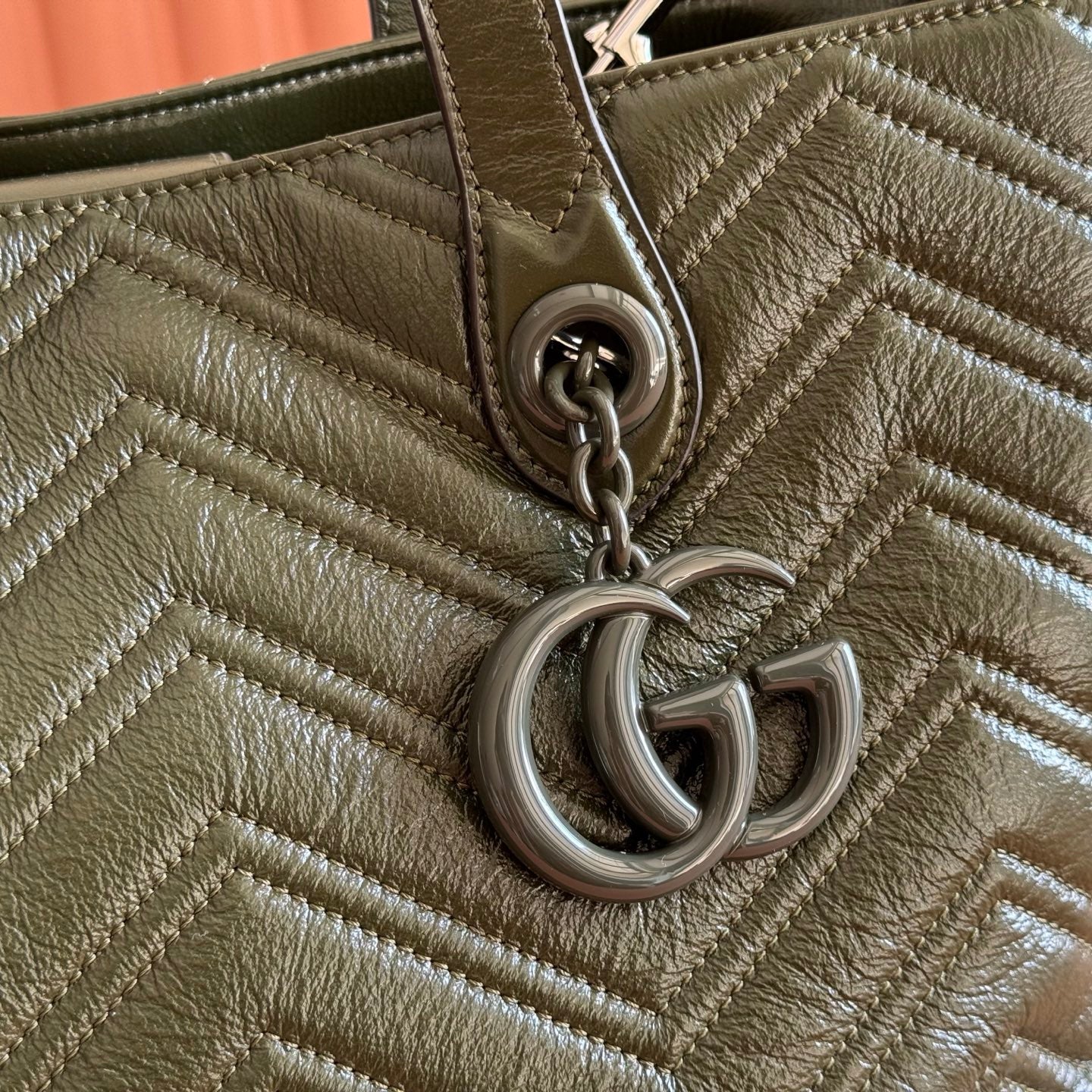 Olive green quilted leather tote close-up of GG chain charm and ring hardware