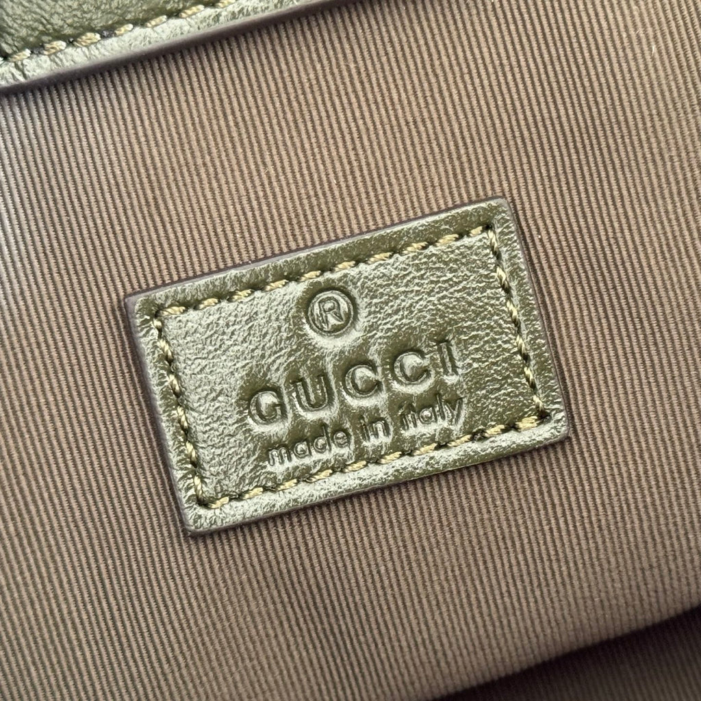 Gucci logo leather patch on beige fabric lining of a dark green bag