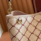 Gucci bag top detail with gold ring hardware and cream strap edge, red lattice print.