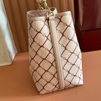Gucci bag side view with cream red lattice print, centered strap seam, gold hardware rings.