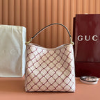 Gucci bag in cream with red interlocking lattice print, top handles, gold-tone hardware.