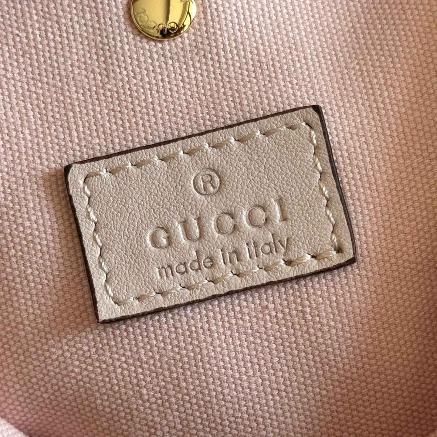 Gucci bag leather label with 'made in Italy' text on beige fabric