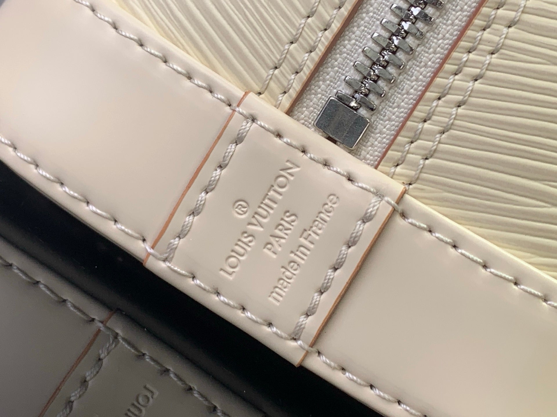 Louis Vuitton logo patch on cream leather strap with visible stitching