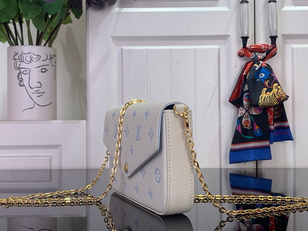 Louis Vuitton crossbody bag with white leather and blue monogram, gold chain strap, side view