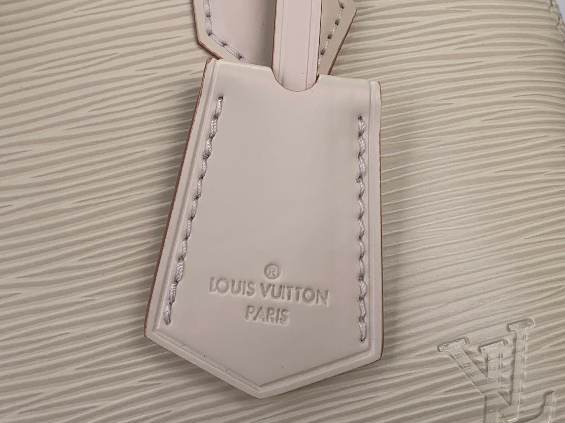 Cream Louis Vuitton leather tag on textured handbag front panel