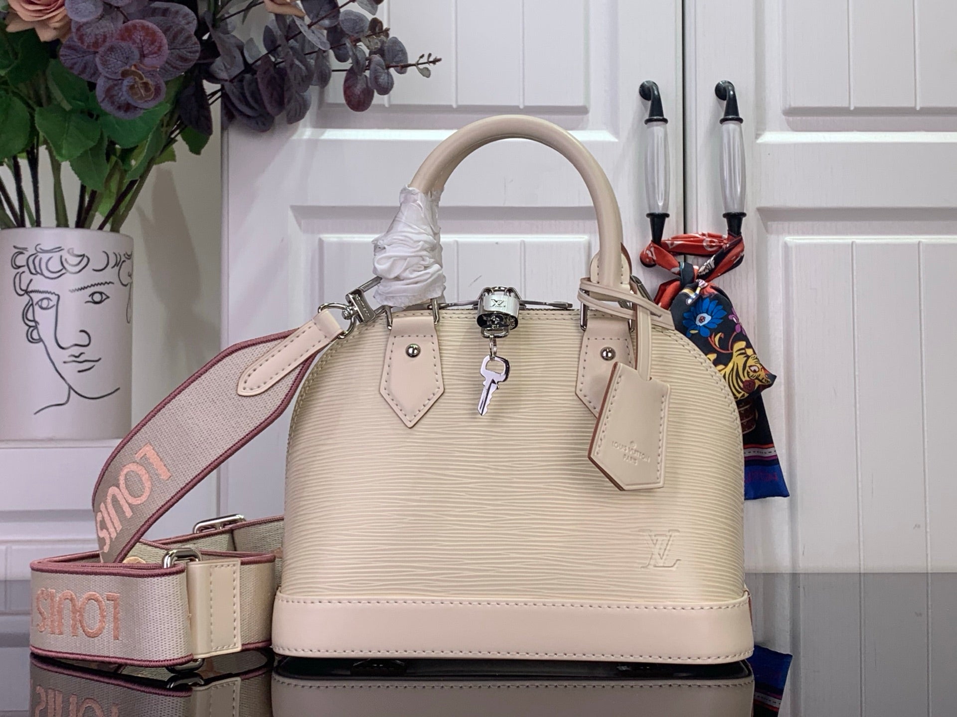 Cream structured Louis Vuitton handbag with top handles, front logo charm and tabs