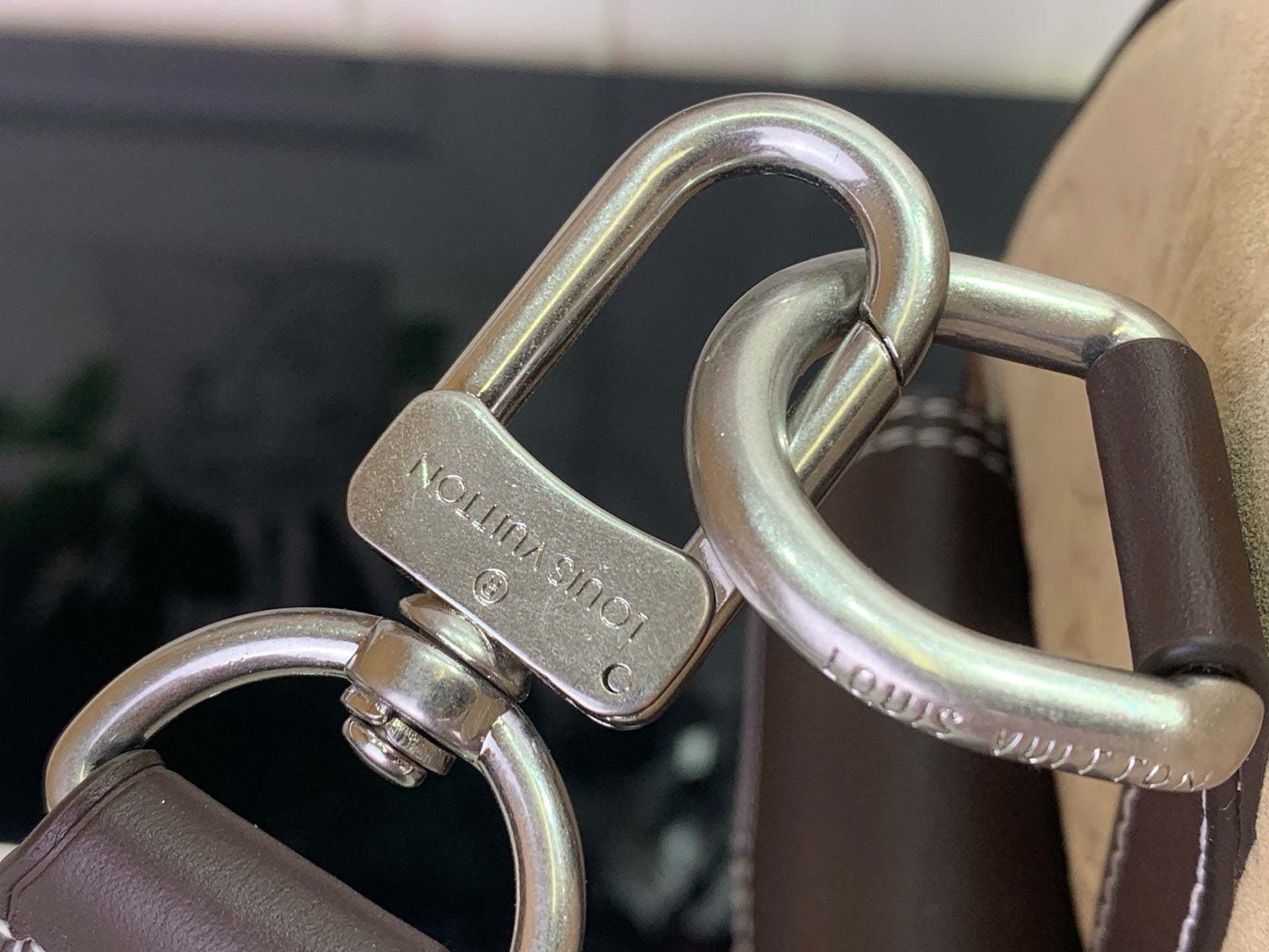 Louis Vuitton metal D-ring hardware with brown leather strap on the bag handle