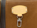 Louis Vuitton bag hardware: gold nameplate with ring key hook on brown leather panel.