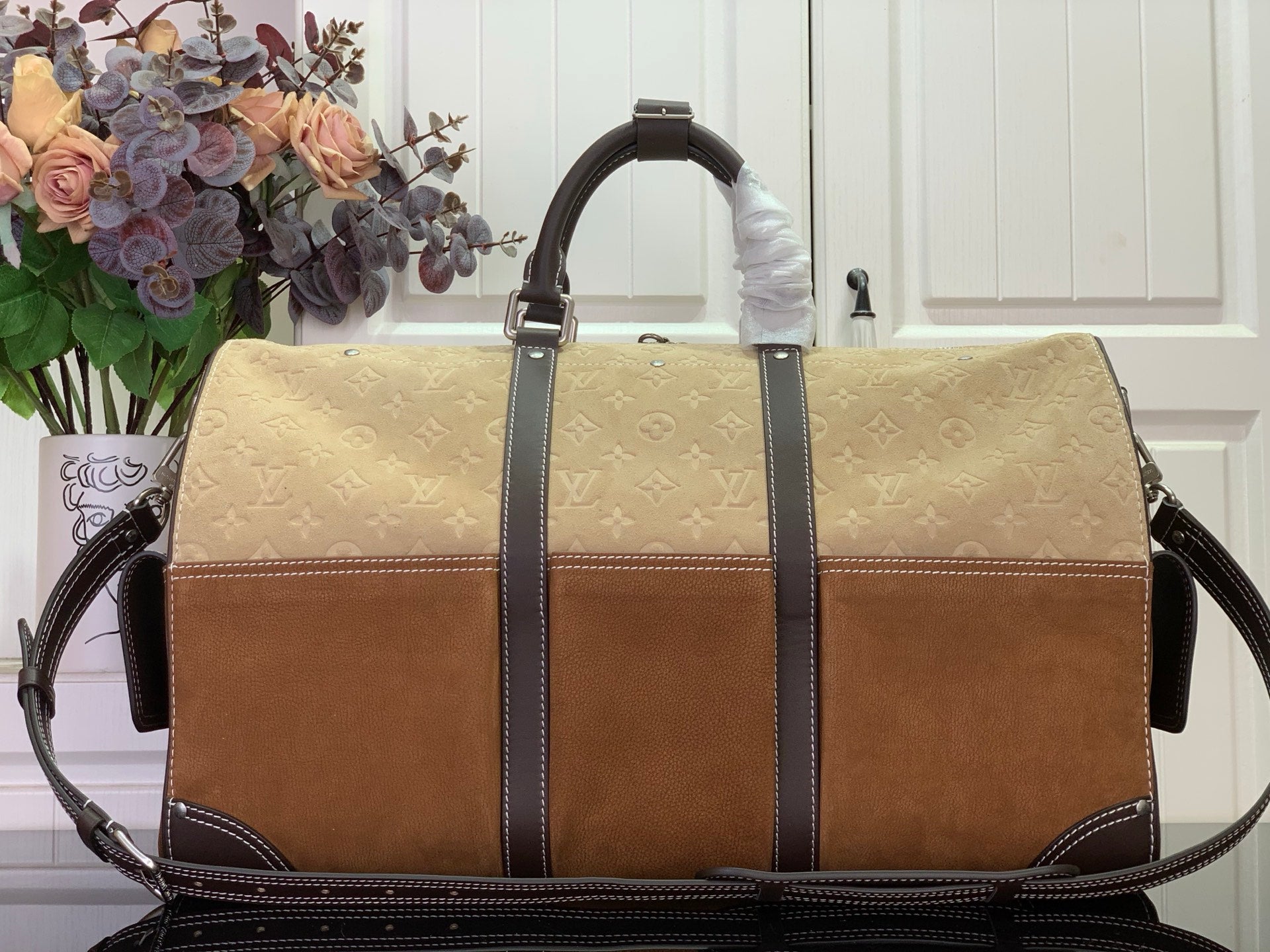Louis Vuitton duffel bag front view in tan monogram canvas with dark vertical leather straps
