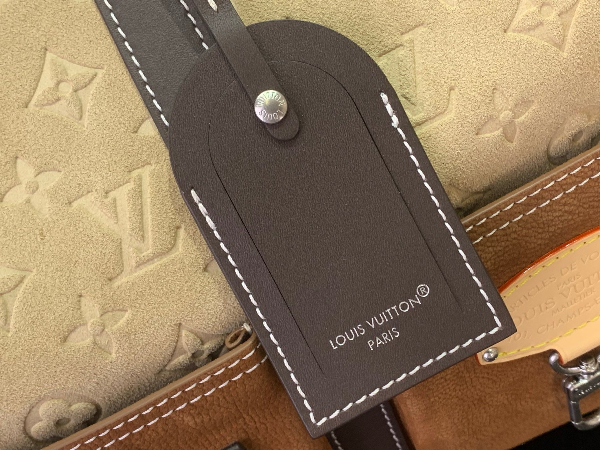 Louis Vuitton luggage tag in dark leather with stitched edges and Paris branding