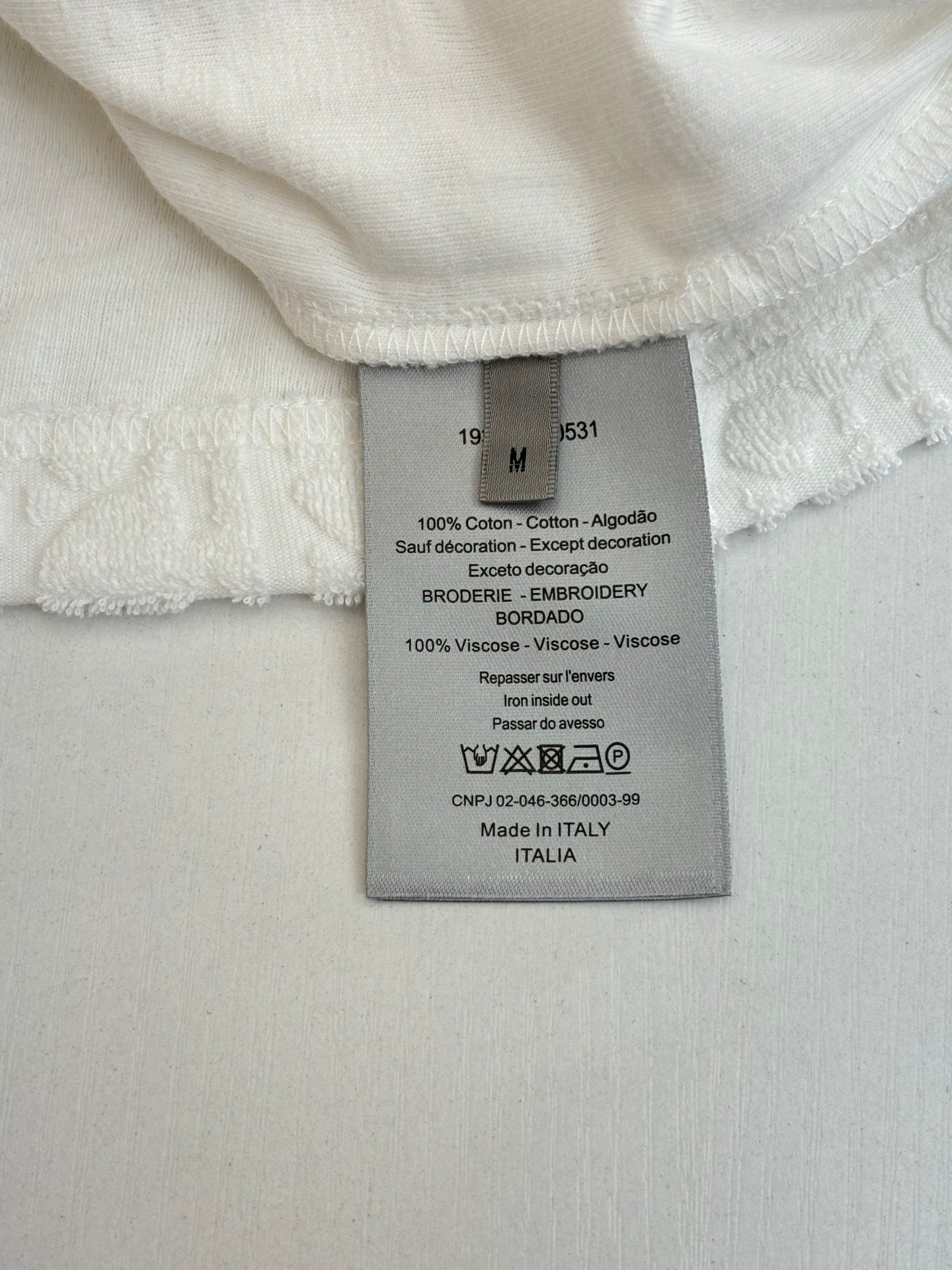 Dior knit top size and fabric care label on white short-sleeve top