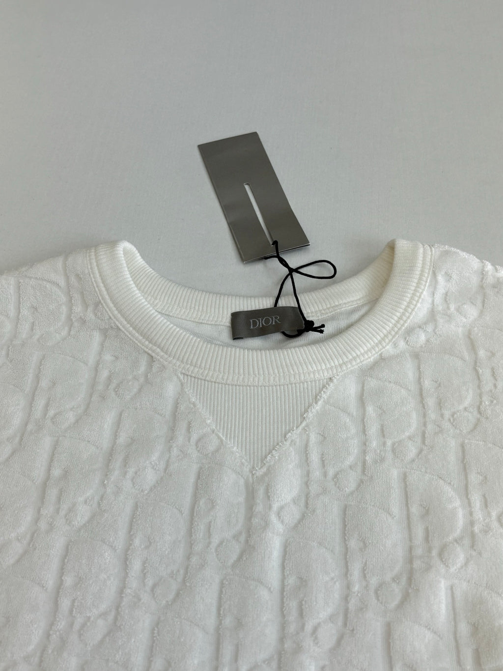 Dior white knit top neckline close-up with crew neck and raised embossed pattern