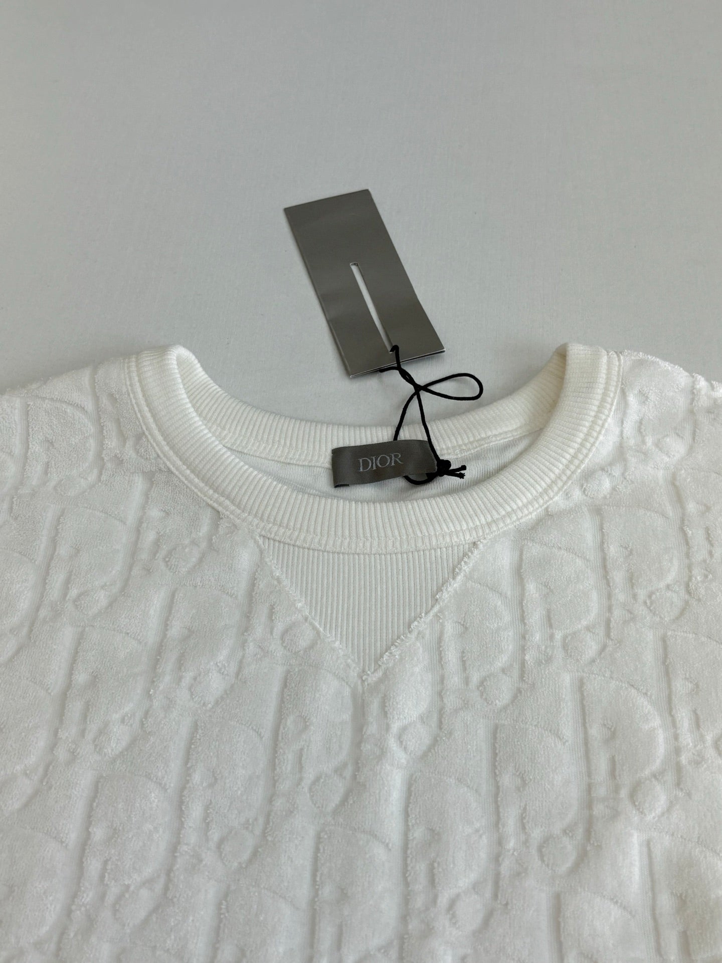 Dior white knit top neckline close-up with crew neck and raised embossed pattern