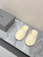 Balenciaga cream slide sandals on display, front logo and open back