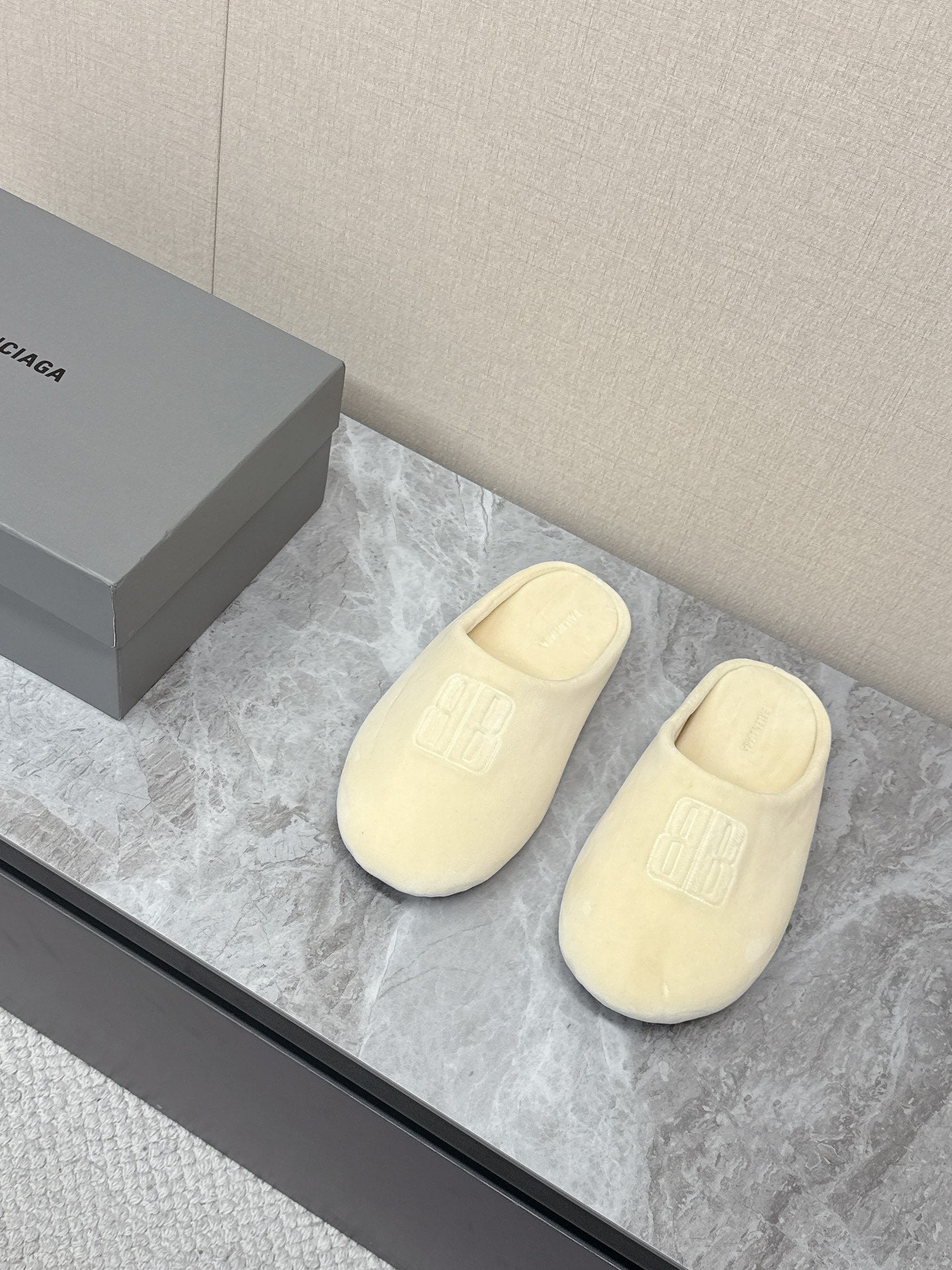 Balenciaga cream slide sandals on display, front logo and open back