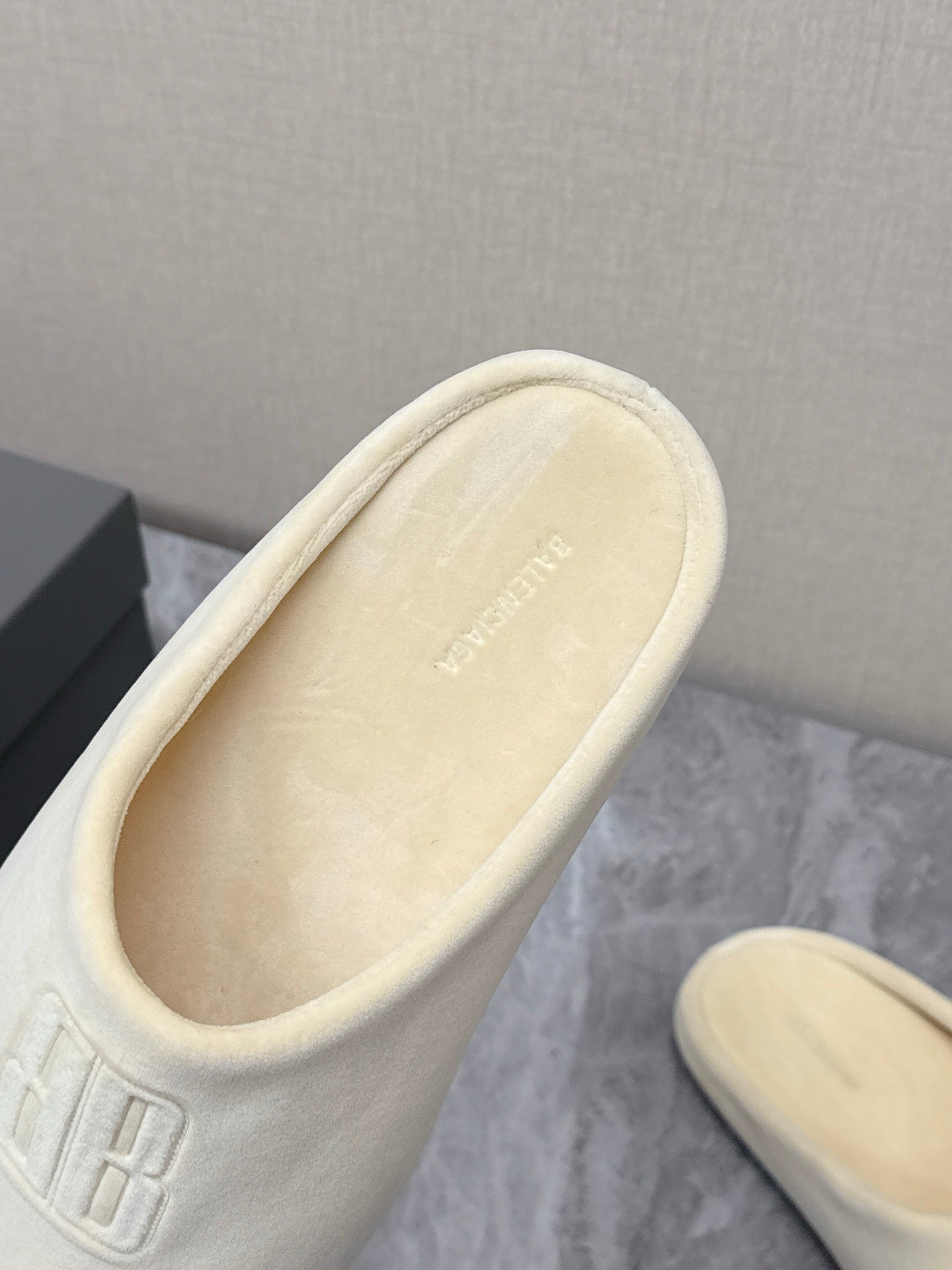 Balenciaga cream slide sandal close-up, embossed logo on cushioned upper
