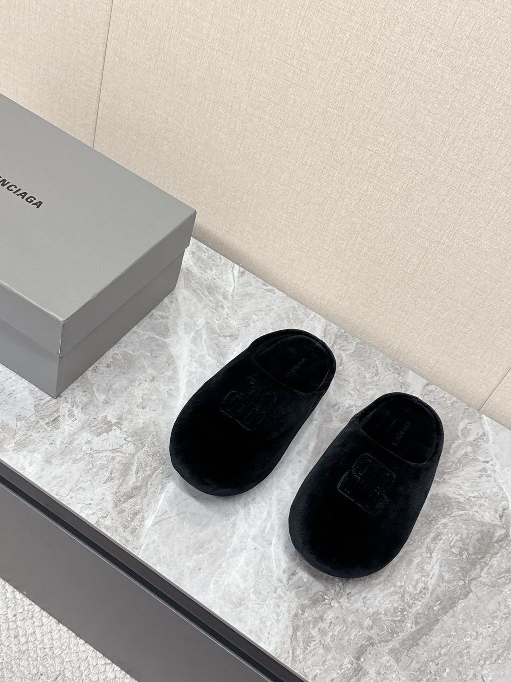 Black slide sandals with embossed Balenciaga logo, pair on display