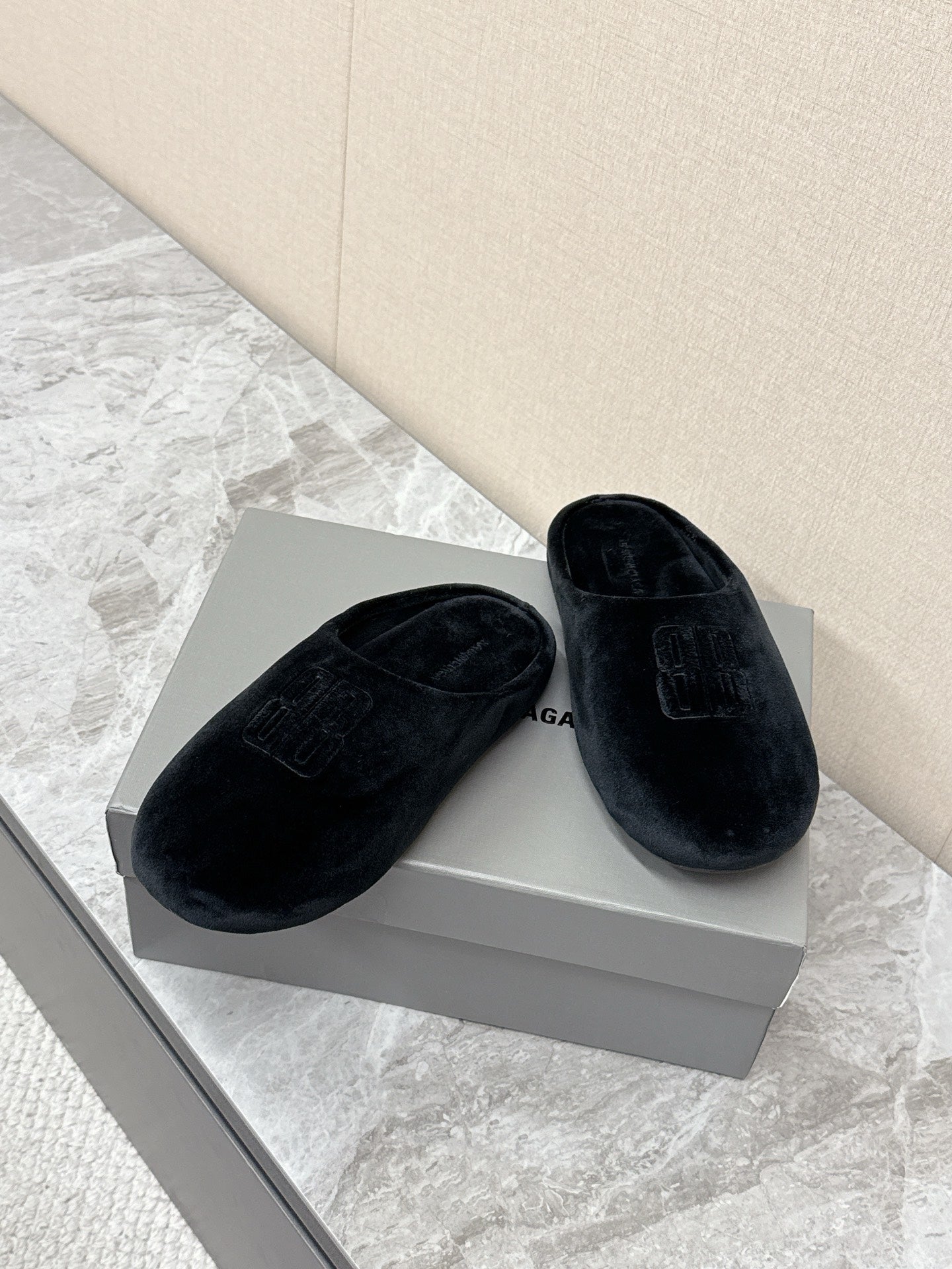 Black slide sandals with embossed Balenciaga logo, laid out side view