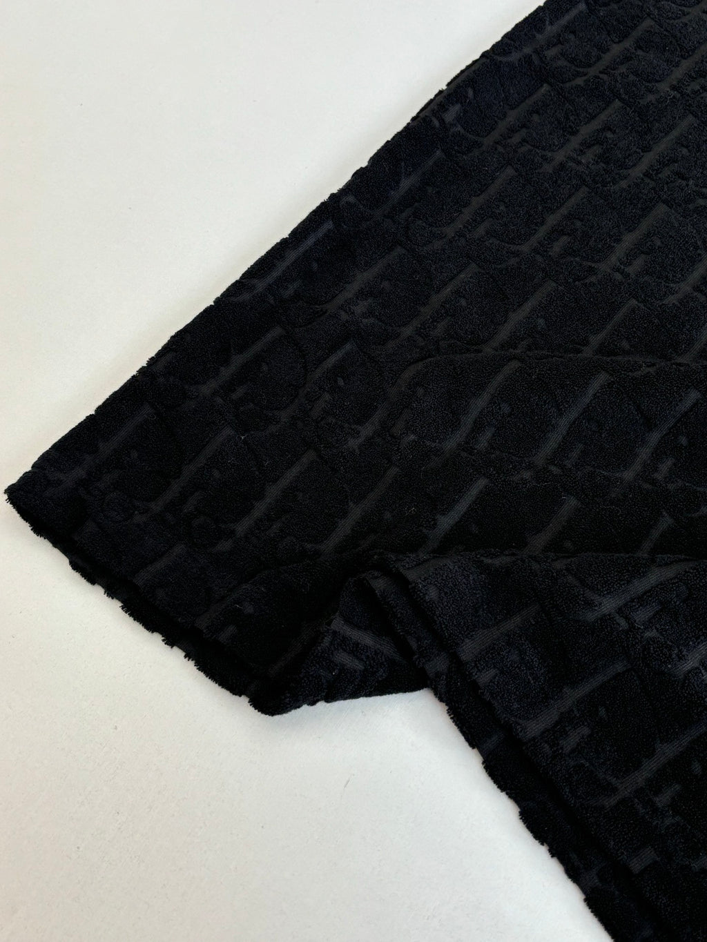 Short-sleeve knit sleeve section, dark textured fabric with raised logo pattern