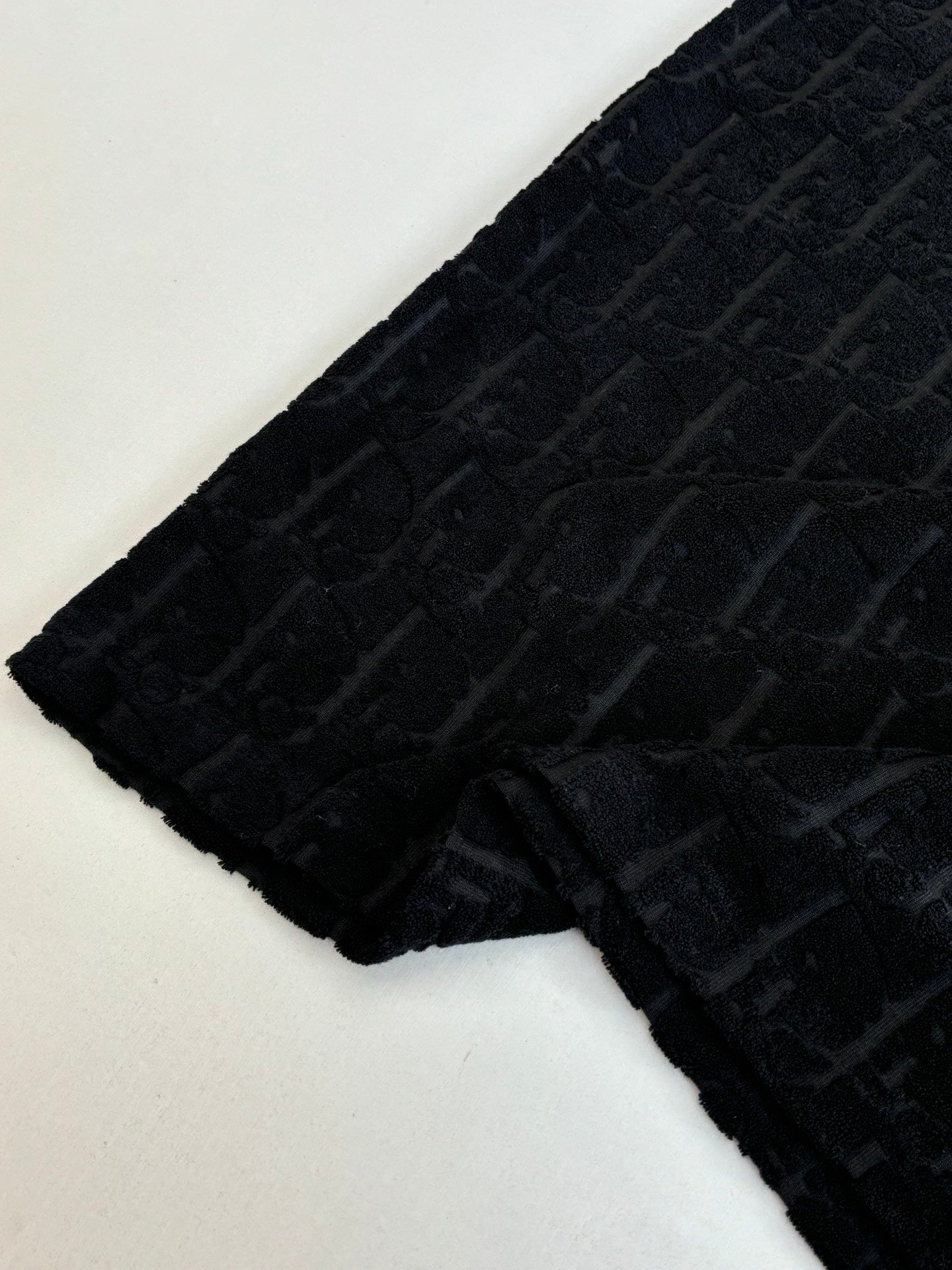 Short-sleeve knit sleeve section, dark textured fabric with raised logo pattern