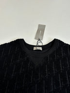 Crew-neck knit top, dark with allover logo texture; close view of neckline