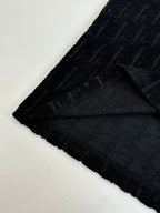 Hem and side view of dark textured knit, with logo pattern and curved bottom