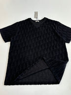 Short-sleeve knit top laid flat, dark textured fabric with logo pattern