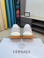 Back view of white/gray lace-up sneakers with tan rubber sole, cushioned heels.