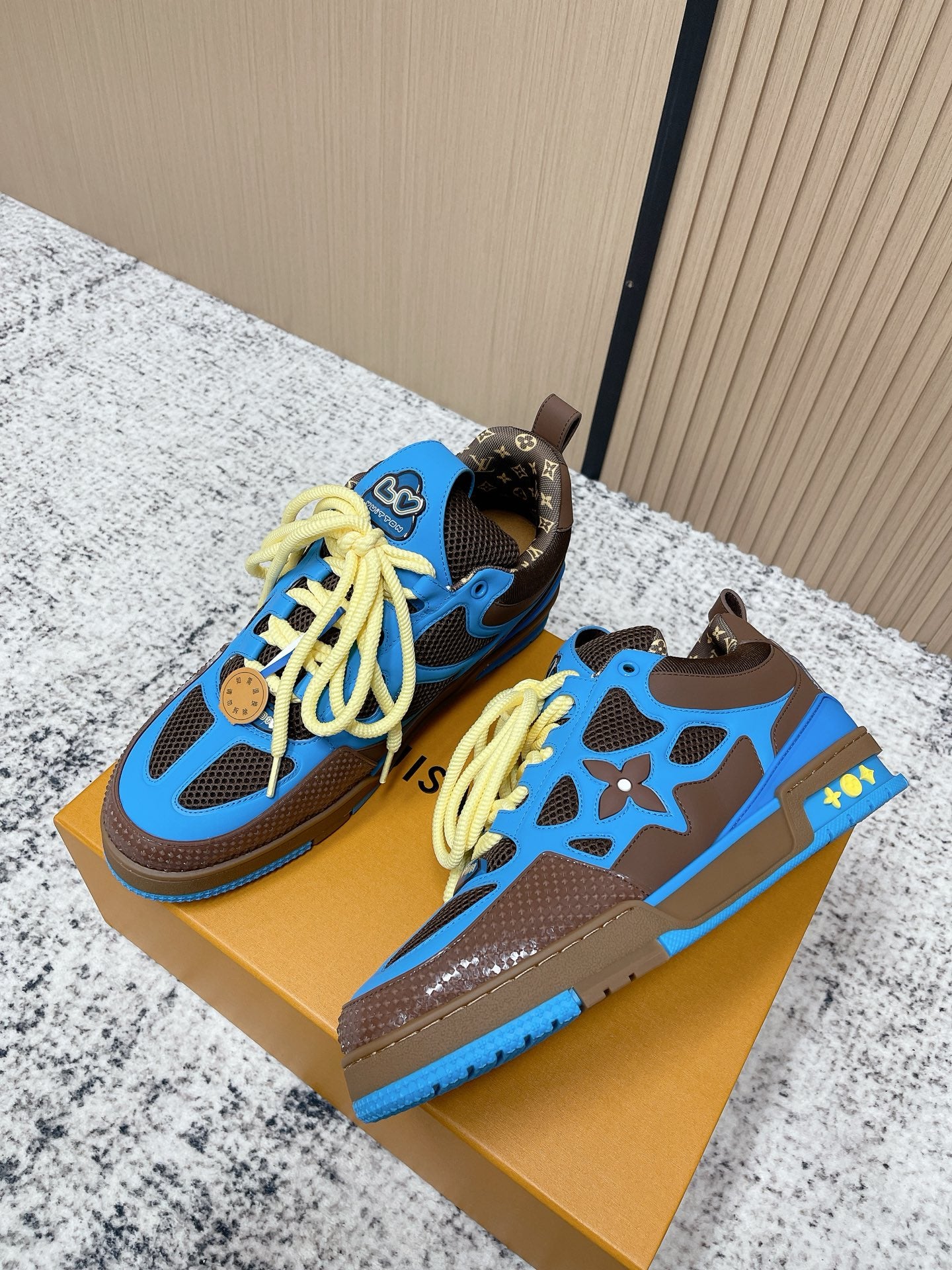 Pair of unisex sneakers, blue uppers with neon yellow laces and star-style cutouts