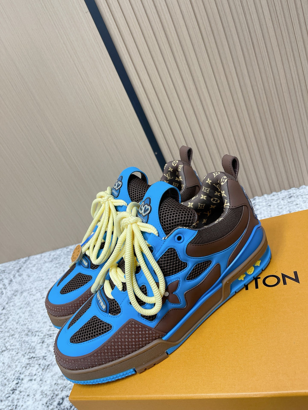 Unisex blue sneakers with dark brown accents and neon yellow laces, shown on box