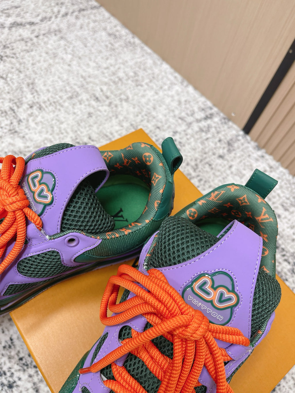 Louis Vuitton unisex sneakers showing green lining, purple panels, orange laces.