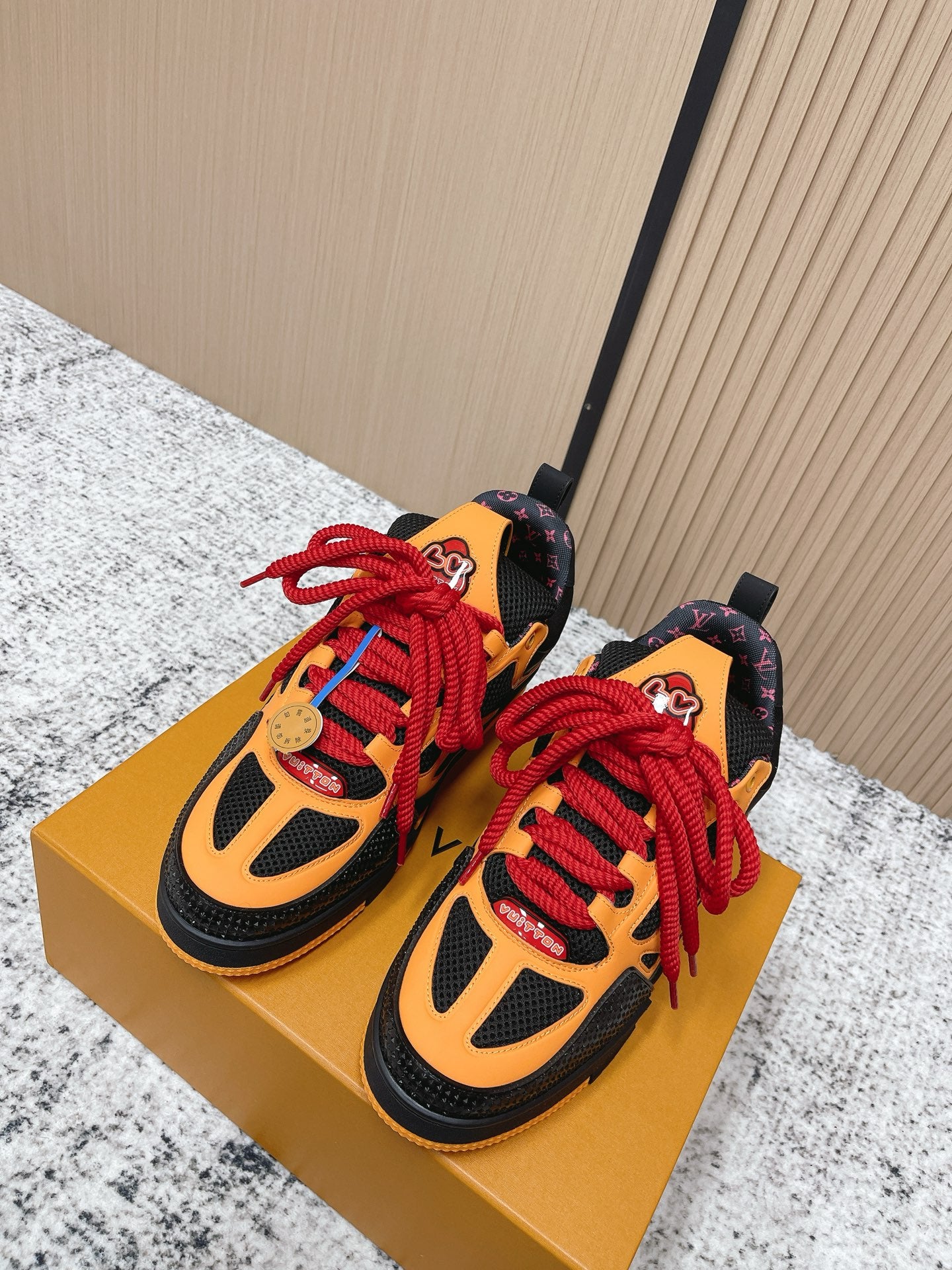 Pair of black, orange and red sneakers with red lace-up and black rubber sole.