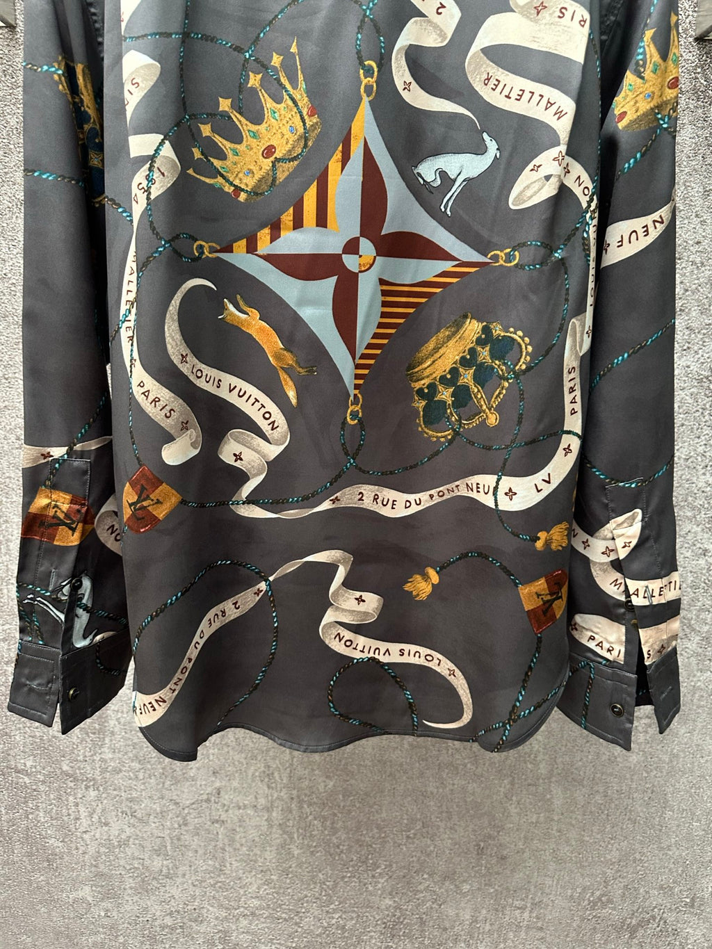 Long-sleeve button-up shirt front view with dark blue central crest and chain design.