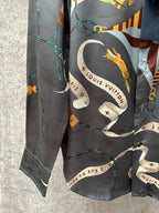 Long-sleeve button-up shirt close-up with golden animal and chain graphic on dark fabric.