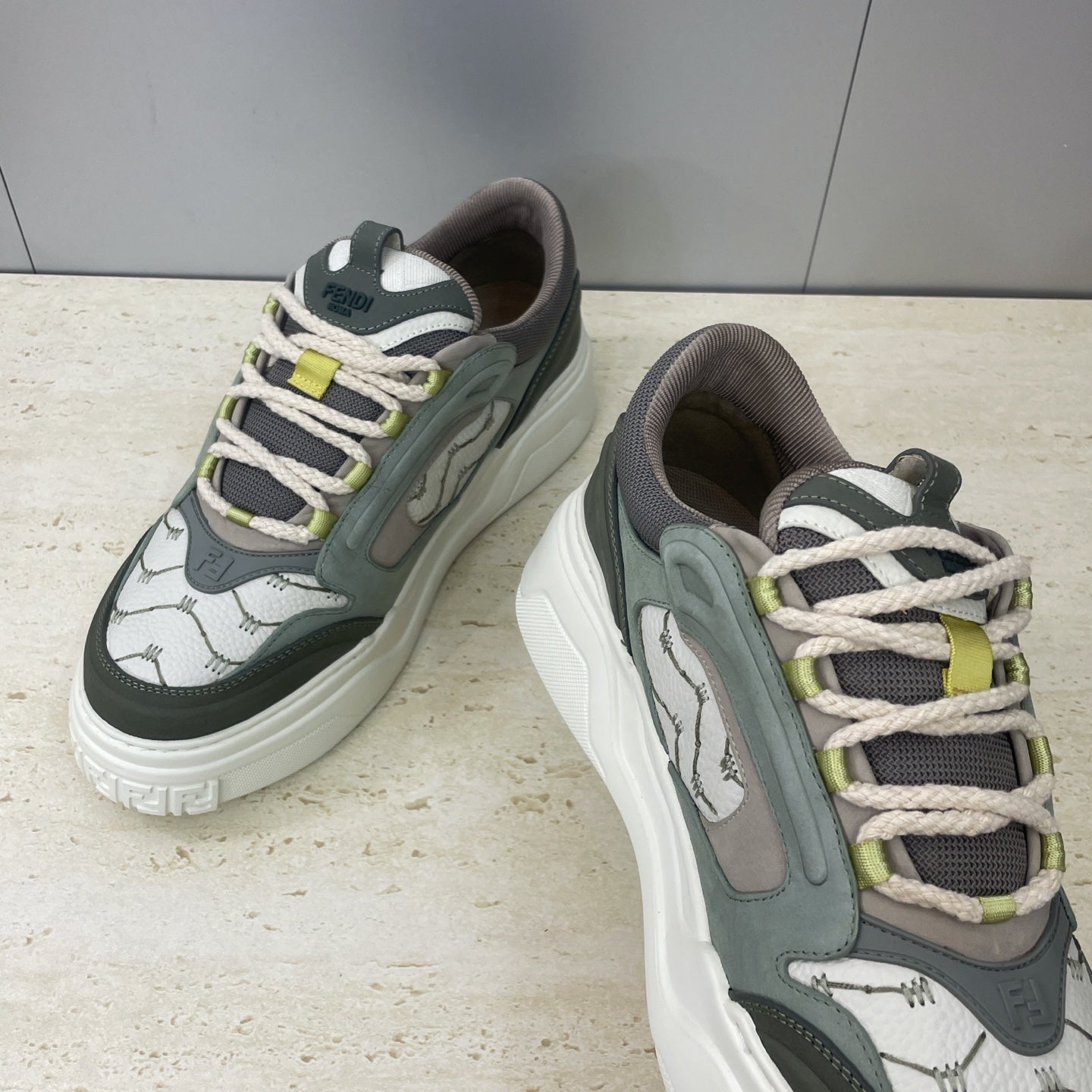 Fendi unisex sneakers, side view with white laces, olive panels, and lime-green accents