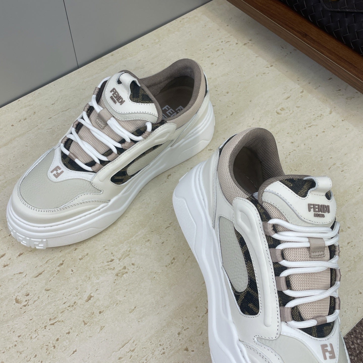Fendi unisex sneakers shown at angle: white upper, black side detail, lace-up front, thick sole.