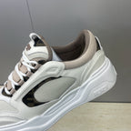 Fendi unisex sneakers close-up on side: white leather look, dark overlay, lace-up eyelets.