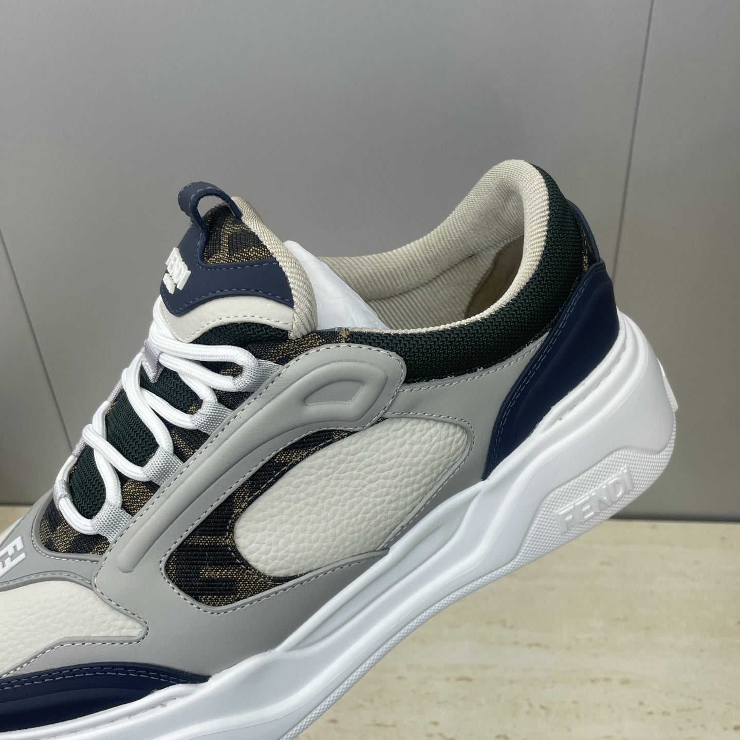 Fendi unisex sneakers close-up, light gray uppers with navy stripe and white laces