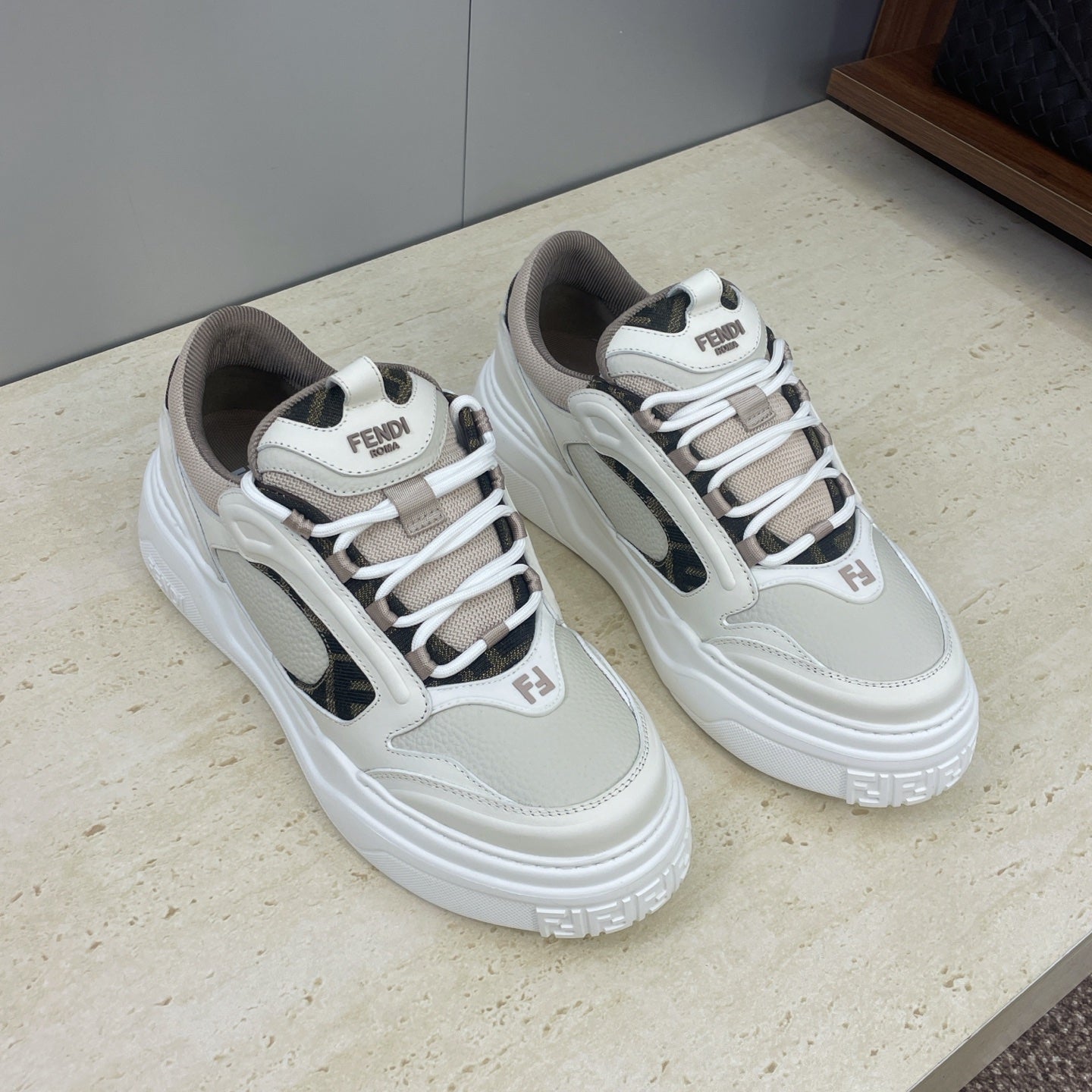 Fendi unisex lace-up sneakers with white uppers, dark swoosh-like panels, and rubber platform sole.