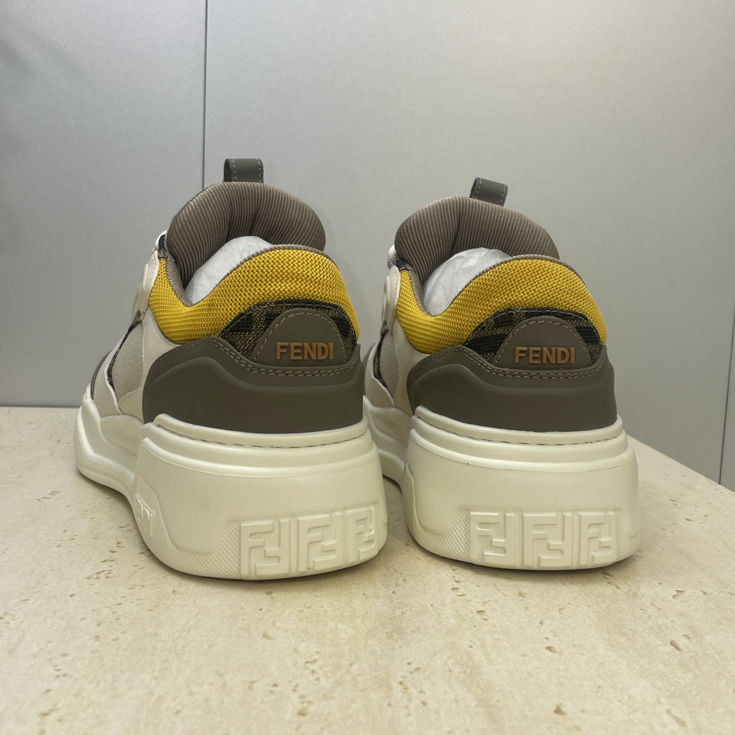 Fendi unisex sneakers heel view, light gray uppers with yellow collar and dark heel logo