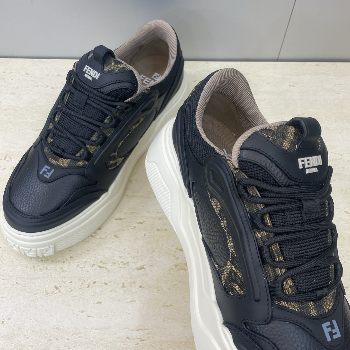 Fendi unisex sneakers close-up: dark navy leather with gold logo trim, thick white sole