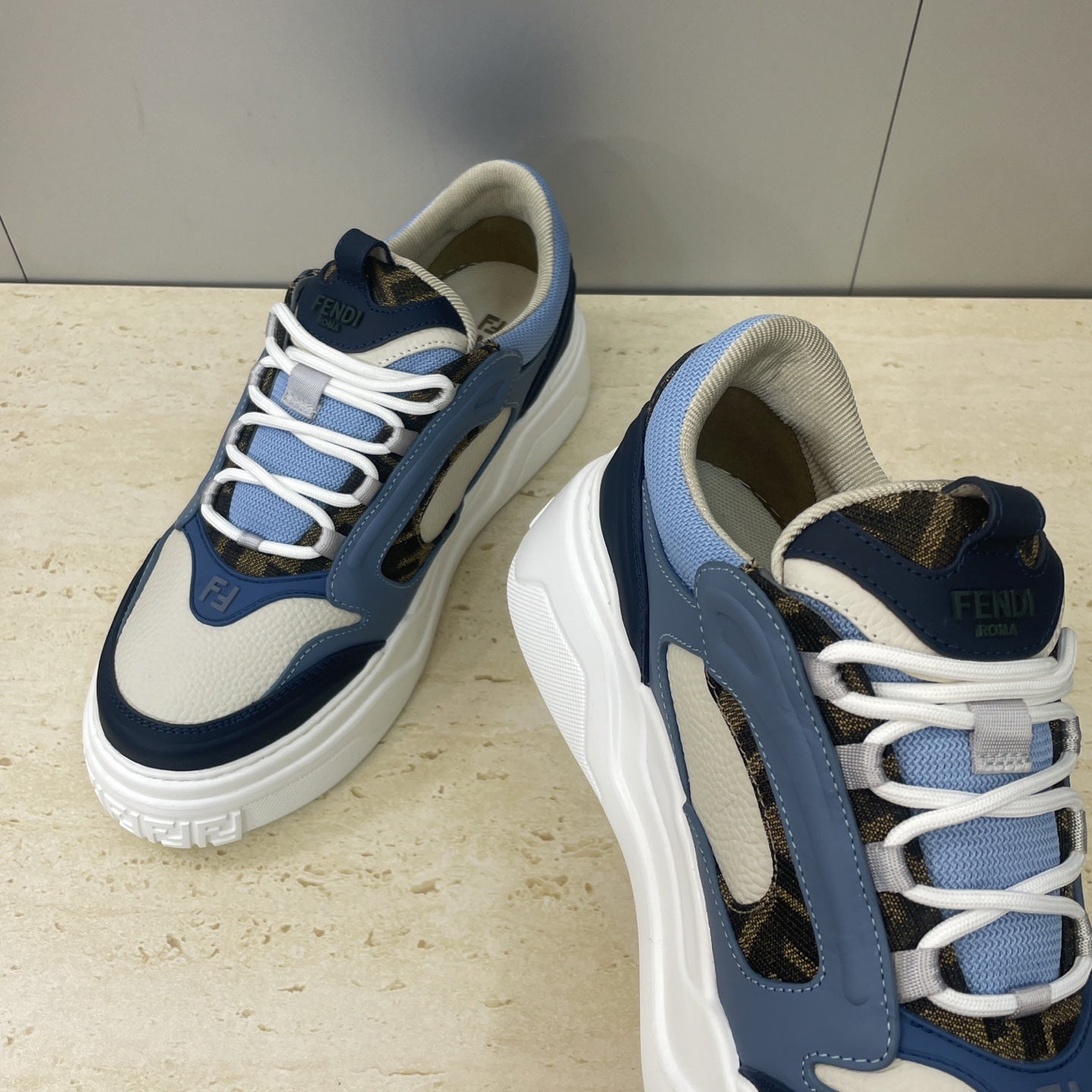 Fendi unisex sneakers close-up, textured navy and blue panels, white laces, thick sole
